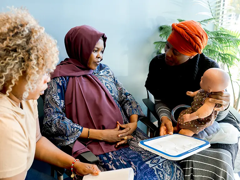 Two women at the Peace Project meet with an pregnant refugee mother.